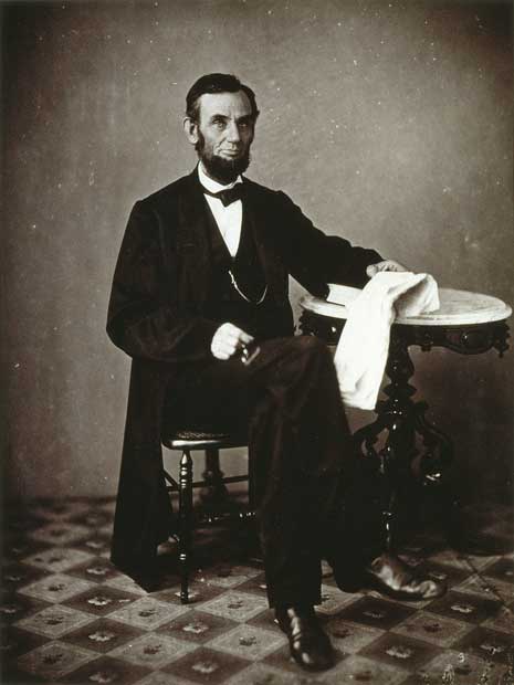 Black and white photograph portrait of Abraham Lincoln, in formal clothing and bowtie, sitting down