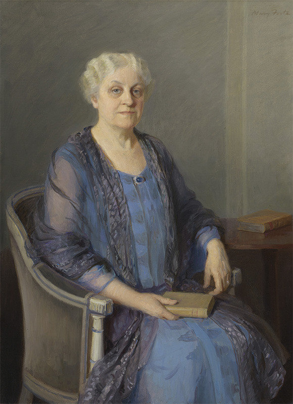 older White woman in a blue dress seated in a chair facing right