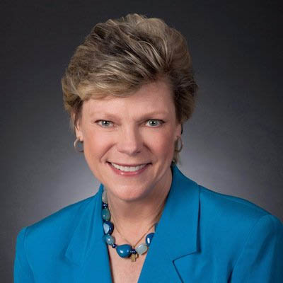 Smiling woman in a blue jacket with a blue necklace
