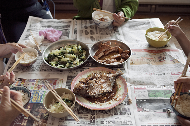 Place settings for a Chinese meal on newspaper