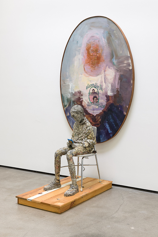 Paper mache sculpture of a man seated in front of a painting