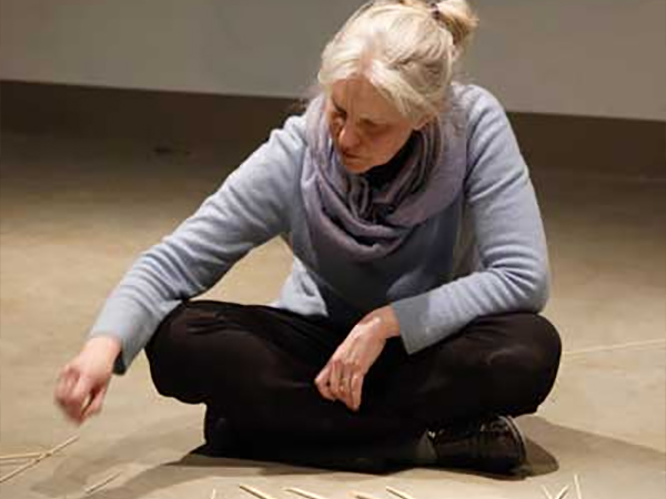 woman sitting on the floor working with sticks