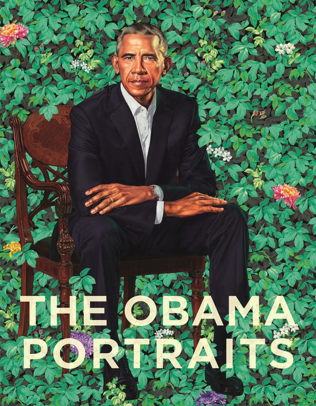 portrait of an African American man in a suit seated in a green leafy setting
