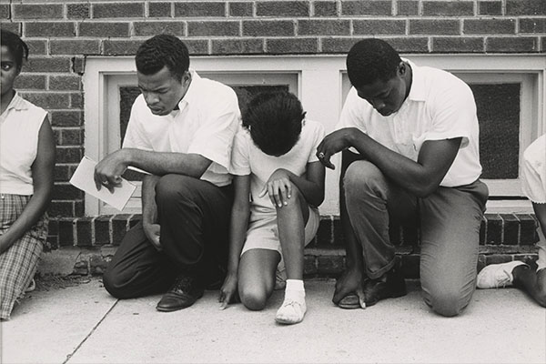 Three African American men keeling and praying