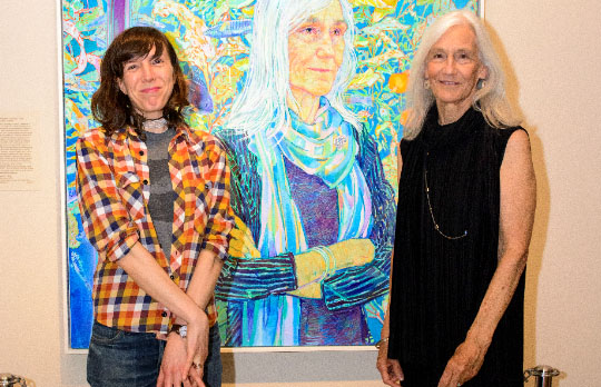 Two women standing in front of a portrait