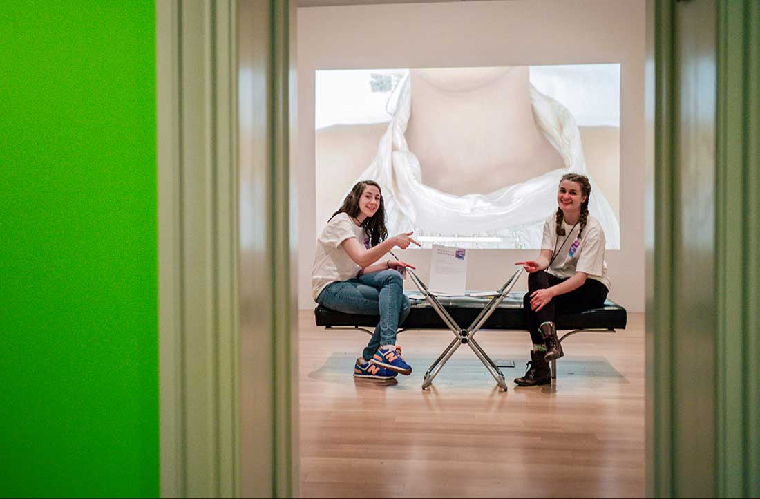 Two teens in the museum galleries, presenting a video portrait of musician Esparanza Spalding