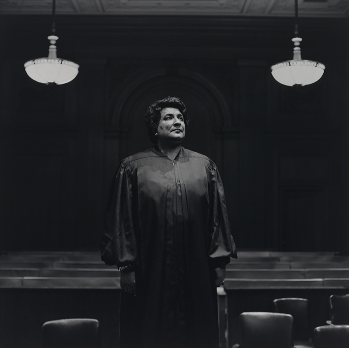 knee length portrait of a woman in judicial robes standing in a courthouse