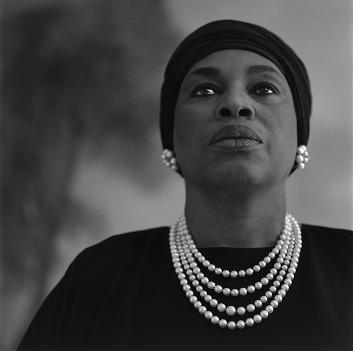 bust length portrait of a woman wearing a black turban, and pearls
