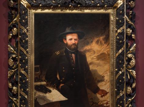 A portrait of a man in a military uniform looking at the viewer and in a beautiful black and gold frame