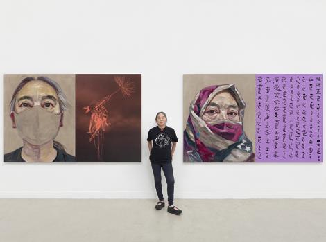 Woman standing between two self-portraits in a studio