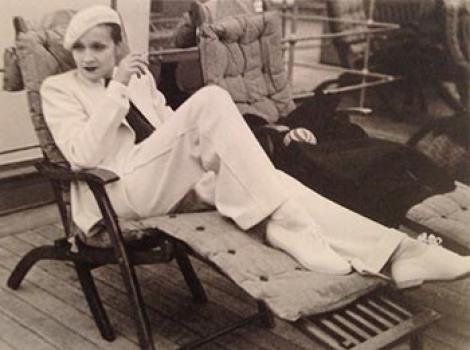 Wonam in a white pantsuit and white beret on a chaise lounge