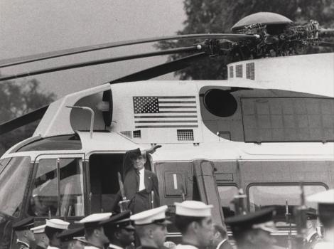 Man waving at a crowd while preparing to board a helicopter