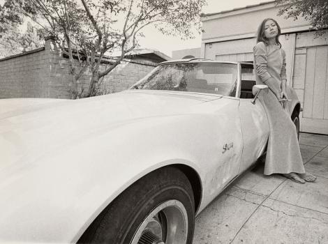 Woman in a long dress standing by a Camero