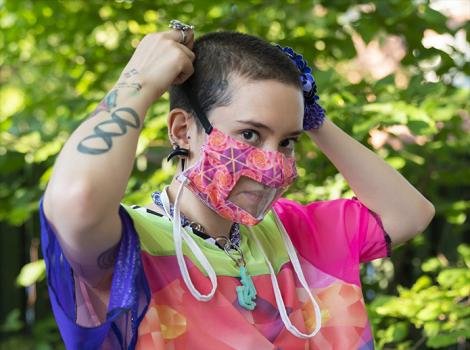 Young woman in colorful clothing adjusting a facemask